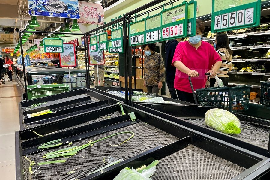 Customers wearing face masks shop next to near-empty shelves at a supermarket following the Covid-19 outbreak in Chaoyang District of Beijing, China, 24 April 2022. (Carlos Garcia Rawlins/Reuters)