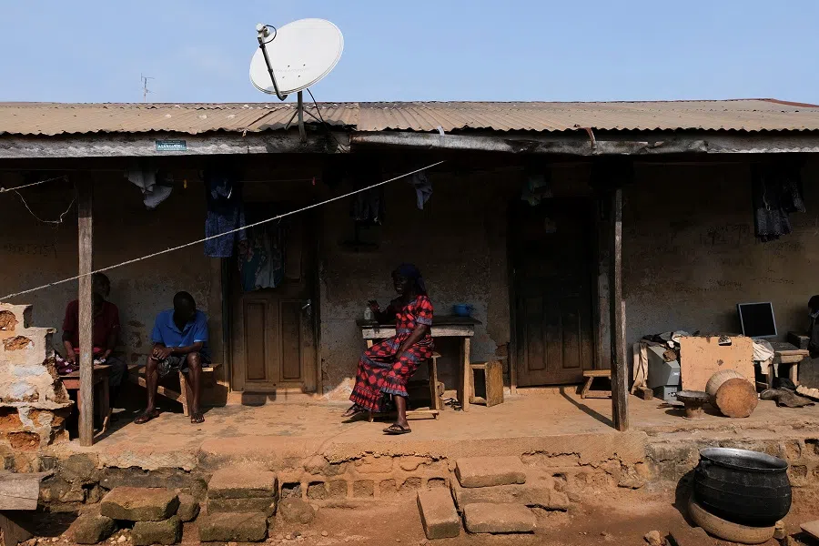 People sit outside a house in the village of Kusa in the Ashanti region of Ghana, 26 August 2022. (Francis Kokoroko/Reuters)