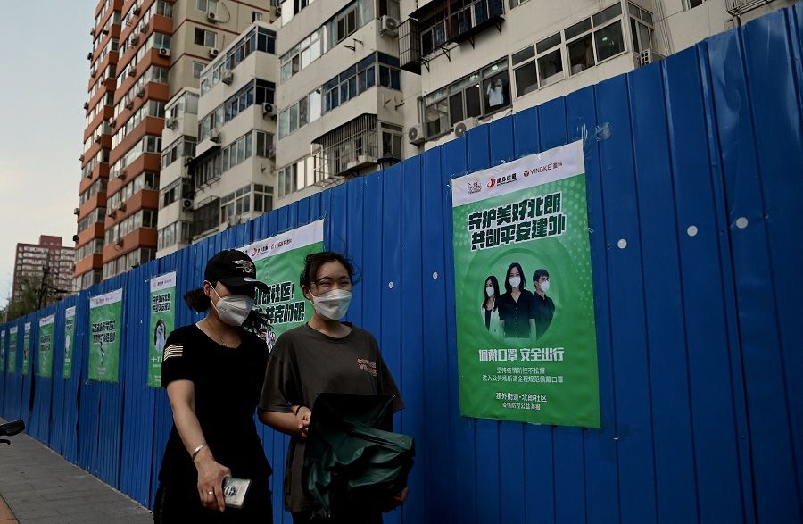 People walk in front of a fenced residential area under lockdown due to Covid-19 restrictions in Beijing, China, on 23 June 2022. (Noel Celis/AFP)