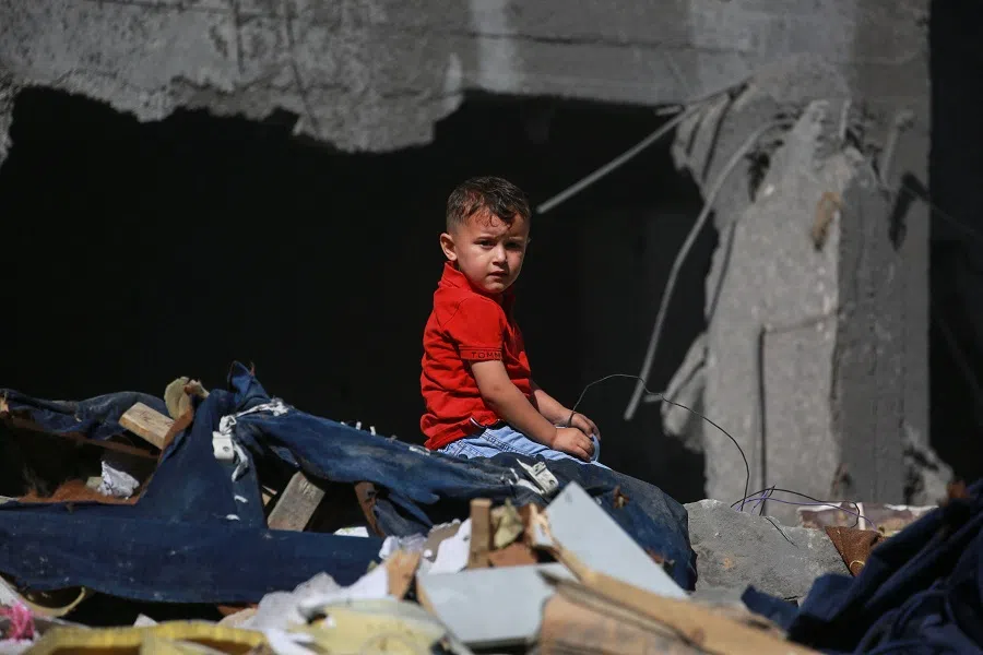 A Palestinian boy sits on the rubble following overnight Israeli strikes in Al-Bureij refugee camp in the central Gaza Strip on 18 June 2024.