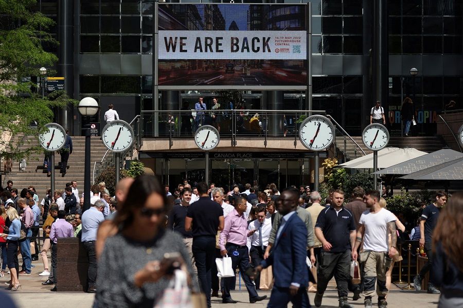 People walk through the financial district of Canary Wharf in London, UK, 18 May 2022. (Kevin Coombs/Reuters)