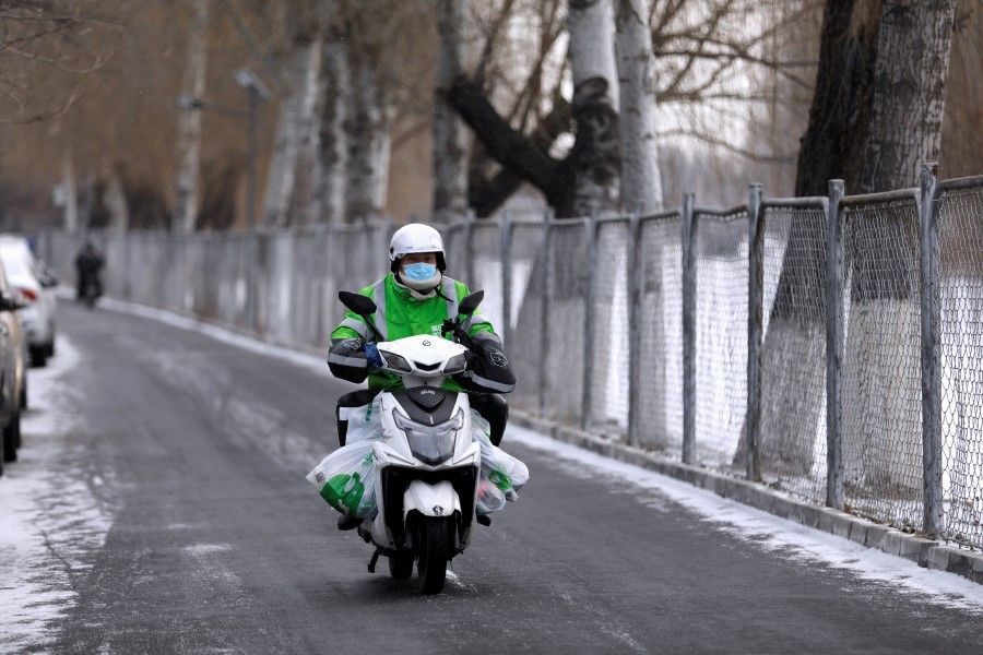 A Meituan delivery worker rides a scooter carrying vegetables on a snowy day in Beijing, China, 19 January 2021. (Tingshu Wang/Reuters)