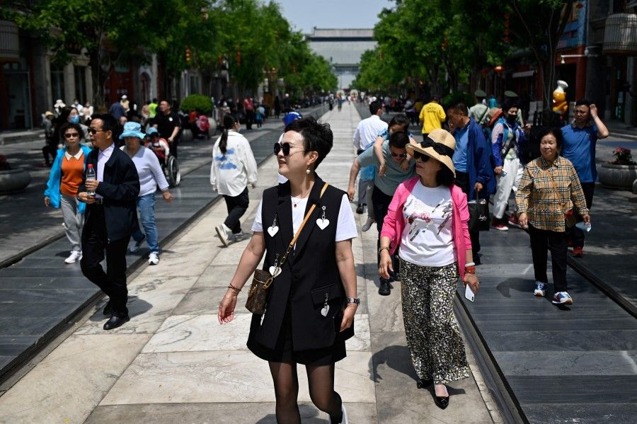 People walk along a street in Beijing on 11 May 2021. (Wang Zhao/AFP)