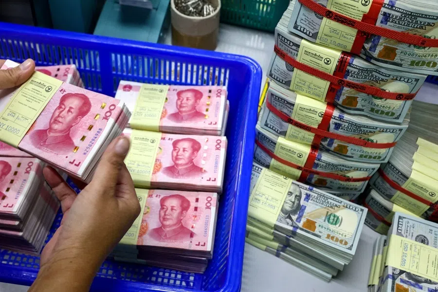 A bank employee count China’s RMB notes next to US dollar notes at a Kasikornbank in Bangkok, Thailand, 26 January 2023.