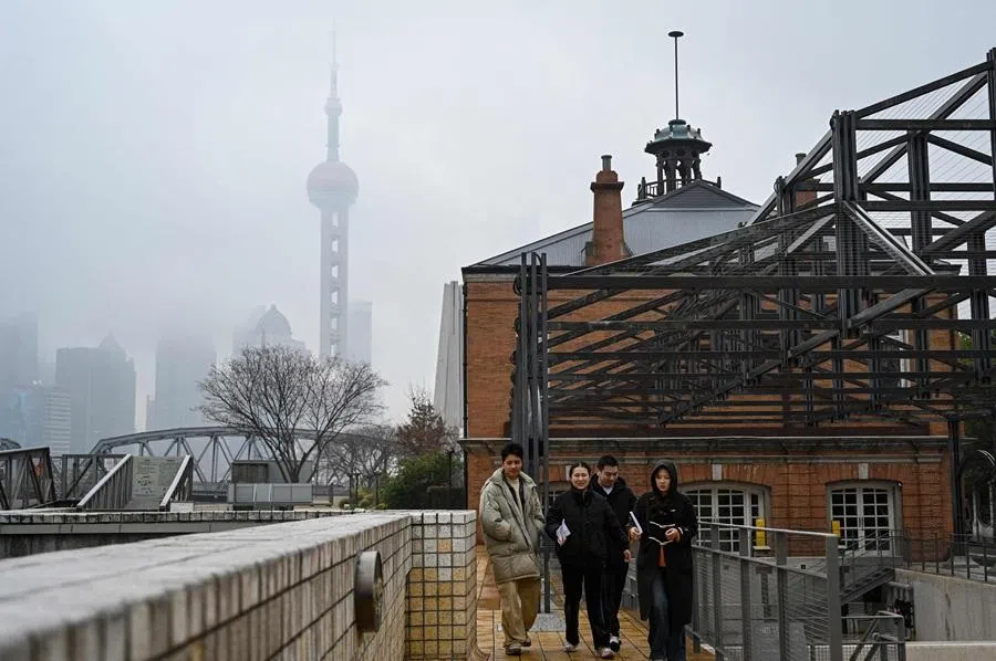People walk along the Suzhou River as the Oriental Pearl Tower is seen behind in Shanghai on 5 March 2026.
