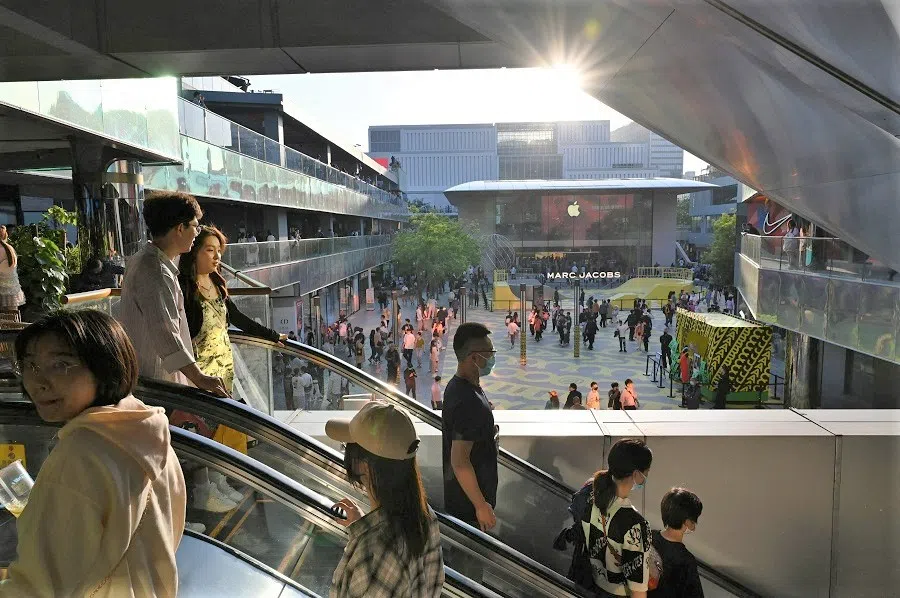 People ride an escalator at a shopping mall in Beijing, China, on 30 April 2023. (Greg Baker/AFP)