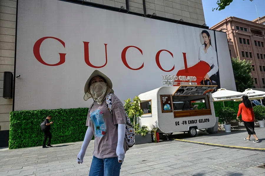 A woman walks past a billboard for Italian luxury fashion brand Gucci at a shopping mall in Beijing, China, on 15 September 2023. (Jade Gao/AFP)