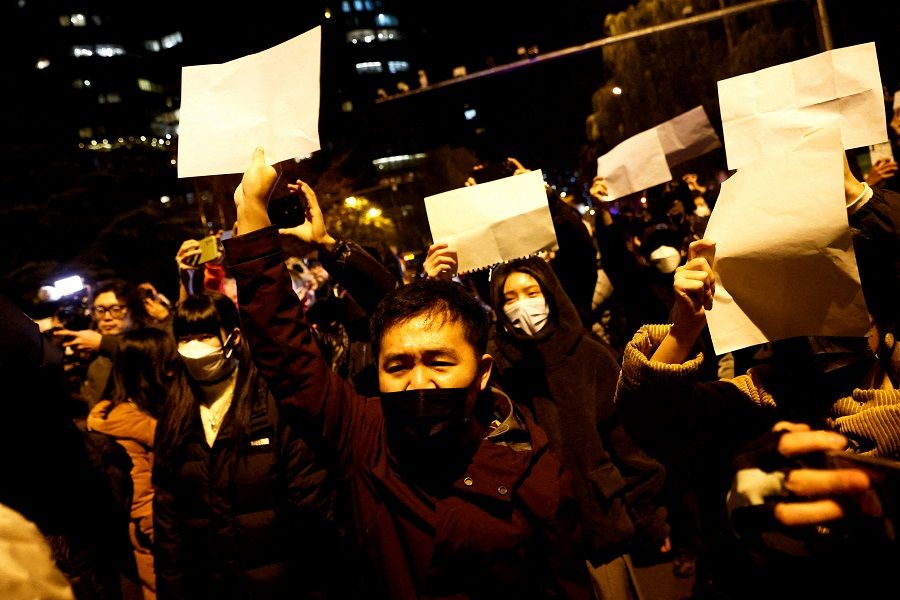 People gather for a vigil and hold white sheets of paper in protest of Covid-19 restrictions, as they commemorate the victims of a fire in Urumqi, in Beijing, China, 27 November 2022. (Thomas Peter/File Photo/Reuters)