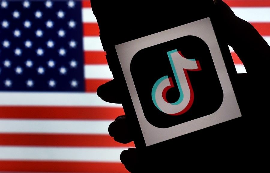 In this photo illustration, the social media application logo, TikTok is displayed on the screen of an iPhone on an American flag background on 3 August 2020 in Arlington, Virginia. (Olivier Douliery/AFP)