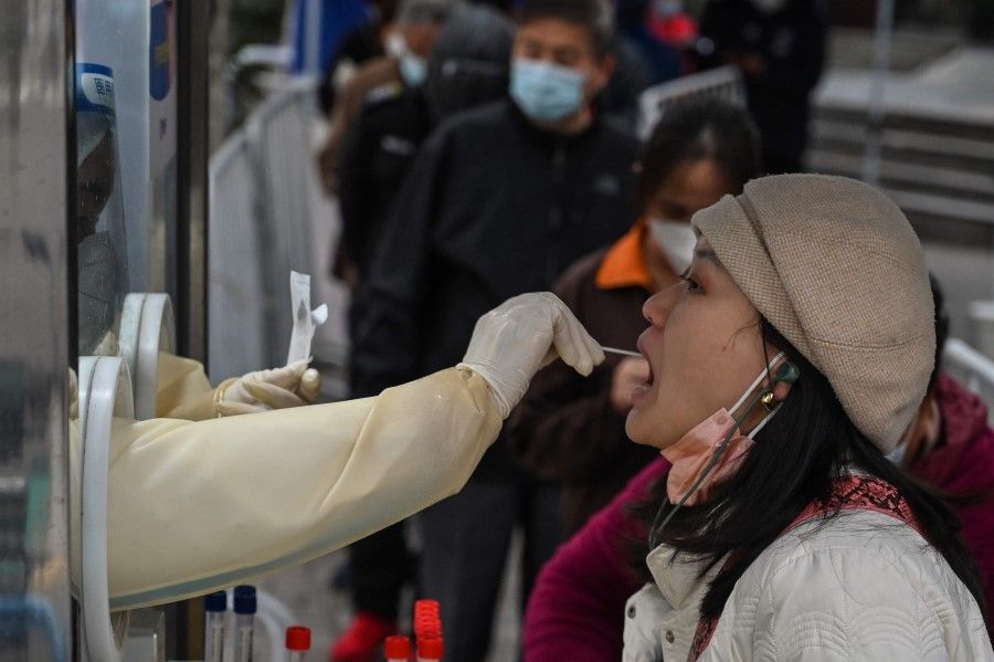 A health worker takes a swab sample from a woman to test for the Covid-19 coronavirus in the Jing'an district in Shanghai on 7 December 2022. (Hector Retamal/AFP)