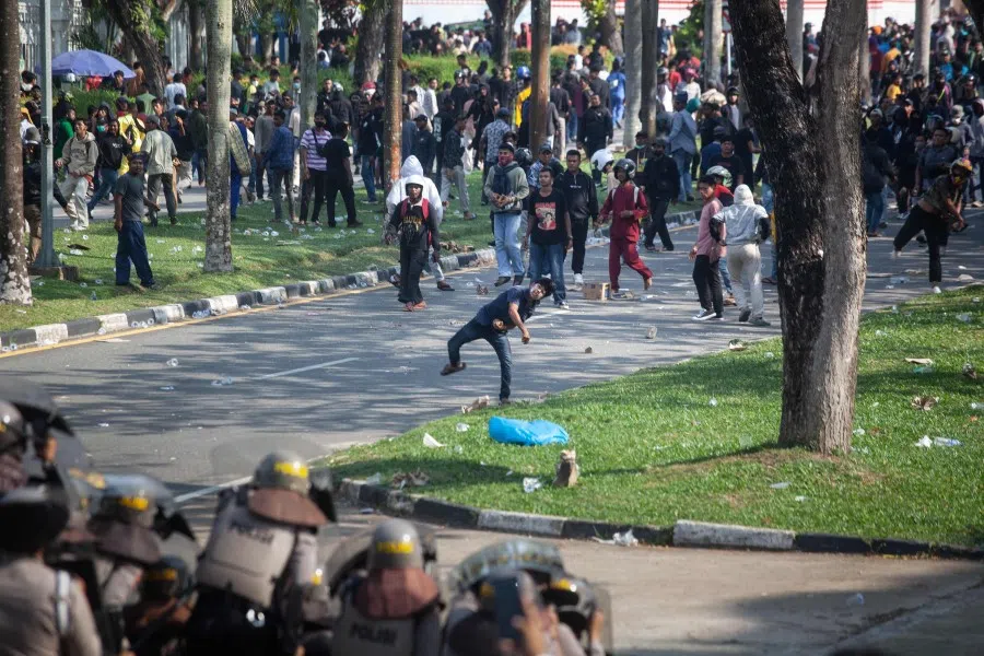 In this picture taken on 11 September 2023, protesters throw stones towards police during a demonstration against a government plan to develop Rempang island into a Chinese-funded economic zone that would displace around 7,500 people, at the Business Entity Batam office in Batam, Indonesia's Riau Islands. (Andaru/AFP)