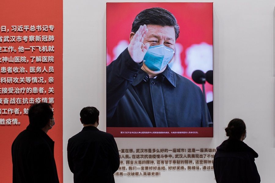 In this picture taken on 15 January 2021, a picture of Chinese President Xi Jinping with a face mask is displayed as people visit an exhibition about China's fight against the Covid-19 coronavirus at a convention centre that was previously used as a makeshift hospital for patients in Wuhan. (Nicolas Asfouri/AFP)