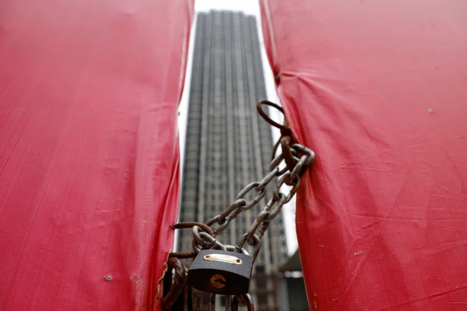 An unfinished residential building is pictured through a construction site gate in Luoyang, China, 16 September 2021. (Carlos Garcia Rawlins/Reuters)