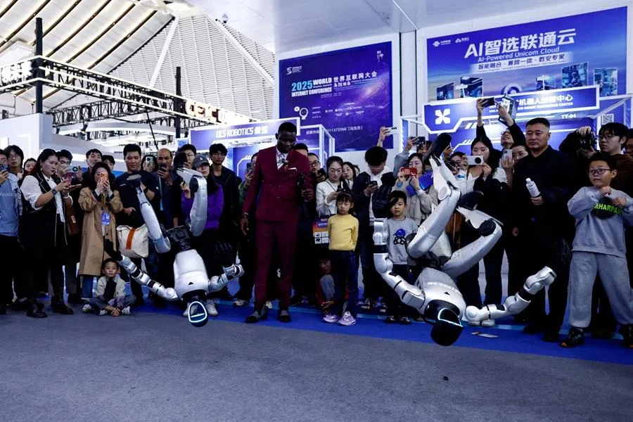 Visitors watch Unitree humanoid robots performing a back flip at the expo of the World Internet Conference in Wuzhen town of Tongxiang city, Zhejiang province, China, on 8 November 2025. (Tingshu Wang/Reuters)