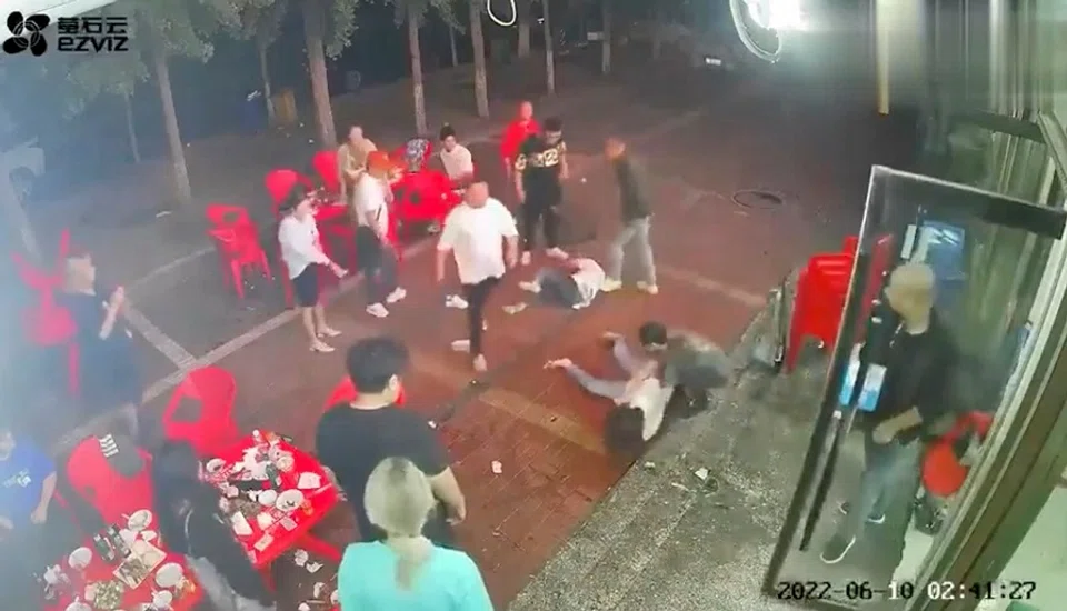 Two women lie on the ground after being assaulted by a group of men outside a restaurant in the city of Tangshan, China, 10 June 2022, in this screen grab taken from surveillance footage obtained by Reuters on 12 June 2022. (Video obtained by Reuters)