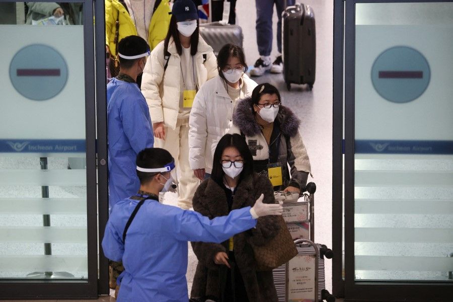 A South Korean soldier wearing personal protective equipment guides a group of Chinese tourists for Covid-19 tests upon their arrival at the Incheon International Airport in Incheon, South Korea, 4 January 2023. (Kim Hong-Ji/Reuters)