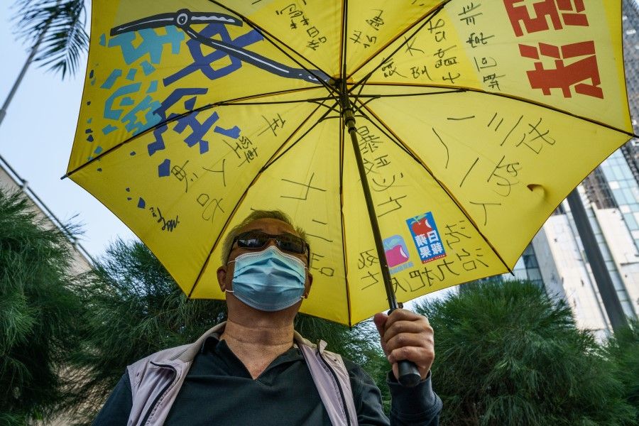A pro-democracy demonstrator holds a yellow umbrella outside the West Kowloon Magistrates' Courts during a hearing for 47 opposition activists charged with violating the city's national security law in Hong Kong, China, 2 March 2021. (Lam Yik/Bloomberg)