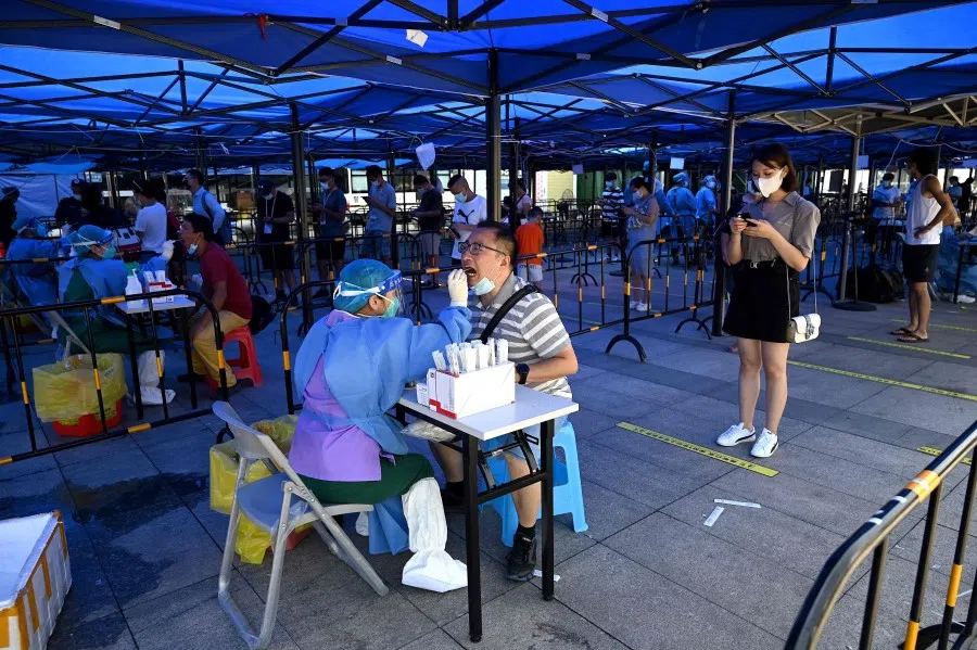 A health worker takes a nucleic acid sample to test for the Covid-19 coronavirus as passengers arrive at the train station in Zhuhai, in southern China's Guangdong province on 27 September 2021. (Noel Celis/AFP)