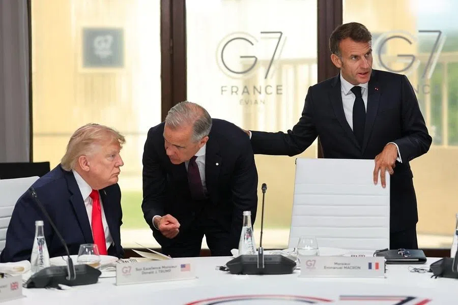 French President Emmanuel Macron stands next to US President Donald Trump and Canadian Prime Minister Mark Carney at a working lunch with leaders of G7 and the Middle East during the G7 summit, in Evian-les-Bains, France, on 16 June 2026.