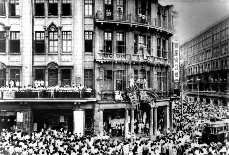 A crowd gathered on Shanghai's Nanjing Road during the Cultural Revolution, tearing down a sign announcing joint ownership of Yong'an Department Store, and sticking slogans on the wall calling for the downfall of capitalism.