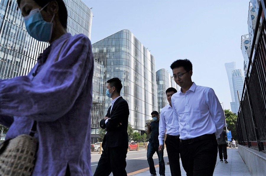 Office workers walk past buildings in Beijing's central business district on 8 September 2021, in China. (Greg Baker/AFP)