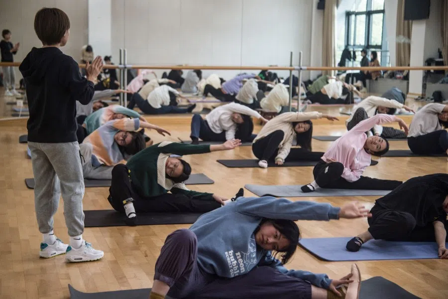 This photo taken on 10 December 2021 shows fitness instructor Sui Lu, a 2012 London Olympic silver medalist, conducting a class at a university in Shanghai. (Jessica Yang/AFP)