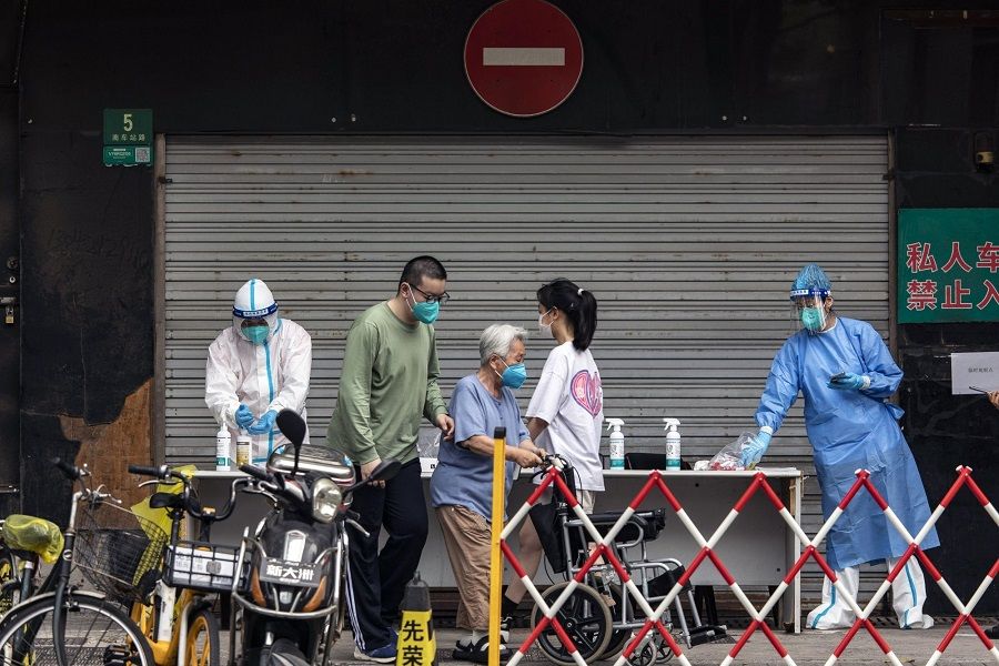 Healthcare workers in protective gear assist residents for Covid-19 tests in Shanghai, China, on 3 July 2022. (Qilai Shen/Bloomberg)