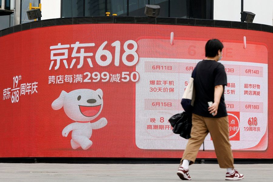 A person walks past a JD.com advertisement for the "618" shopping festival displayed outside a shopping mall in Beijing, China, 14 June 2022. (Carlos Garcia Rawlins/File Photo/Reuters)