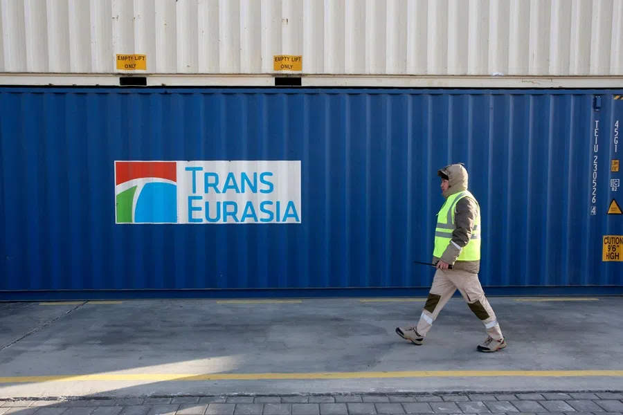 An employee walks past stacked cargo containers at the terminal of the railway station of Dostyk at the Kazakh-Chinese border, a key hub for trade between China and Europe through Central Asia, on 19 November 2025.