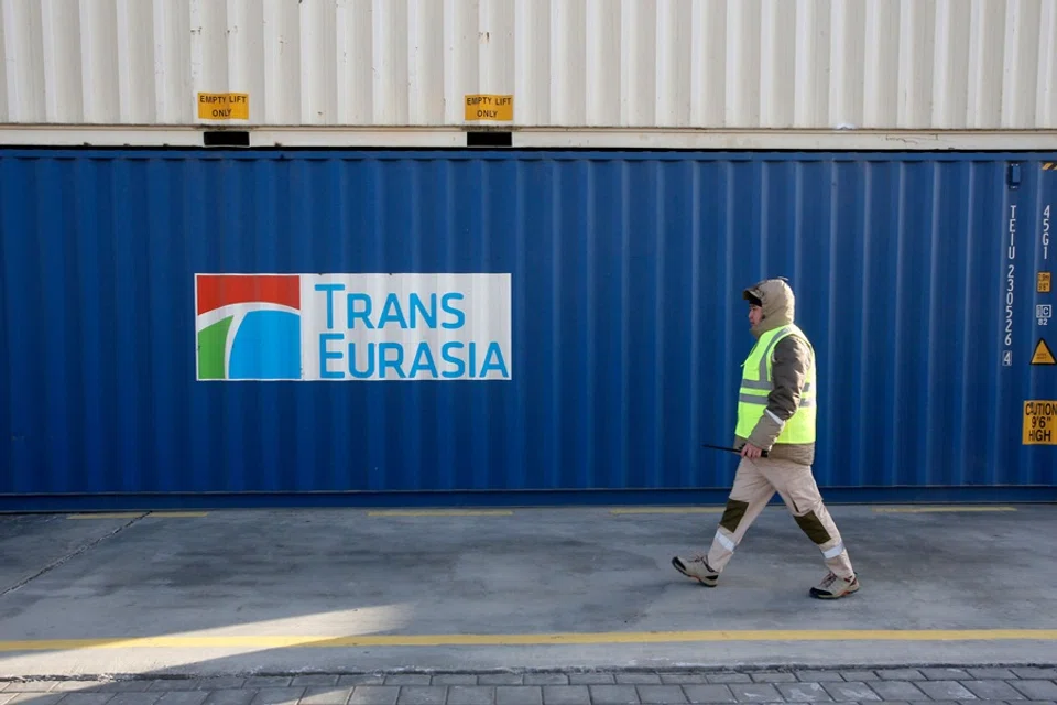 An employee walks past stacked cargo containers at the terminal of the railway station of Dostyk at the Kazakh-Chinese border, a key hub for trade between China and Europe through Central Asia, on 19 November 2025. (Ruslan Pryanikov/AFP)