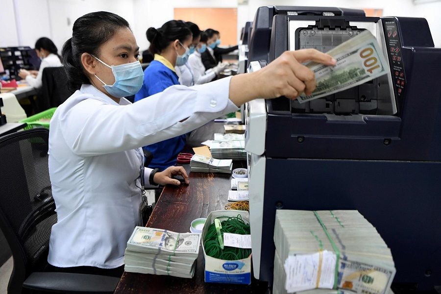 ACLEDA Bank employees count US currency inside the bank in Phnom Penh on 25 May 2020. (Tang Chhin Sothy/AFP)