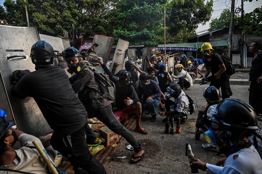 Protesters take cover behind homemade shields in Yangon, Myanmar, on 16 March 2021. (STR/AFP)