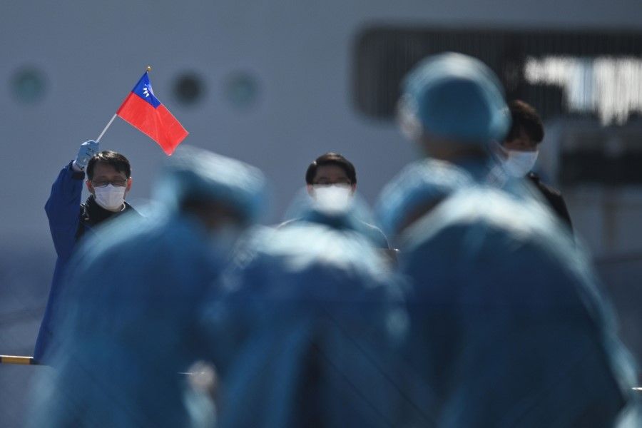 A man (L) holds a Taiwan flag as passengers disembark from the Diamond Princess cruise ship. (Philip Fong/AFP)
