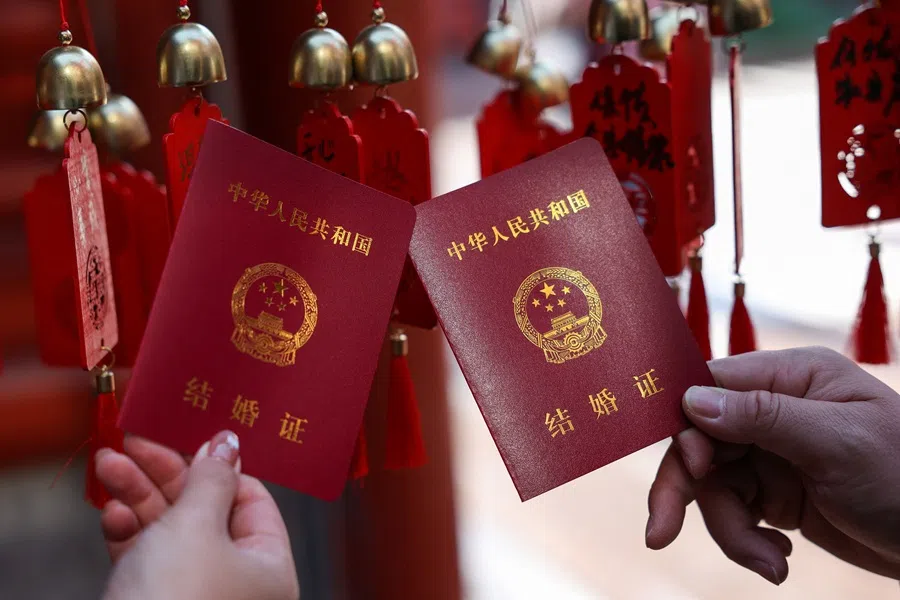 A newlywed couple holds their marriage certificates at the Huguo Guanyin Temple, in Beijing, China, on 28 October 2025. (Tingshu Wang/Reuters)
