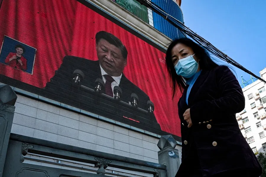 This file photo taken on 16 October 2022 shows an outdoor screen displaying the live speech of Chinese President Xi Jinping from Beijing during the opening session of the 20th Party Congress, as a pedestrian walks past in Yan'an, Shaanxi province, China. (Jade Gao/AFP)