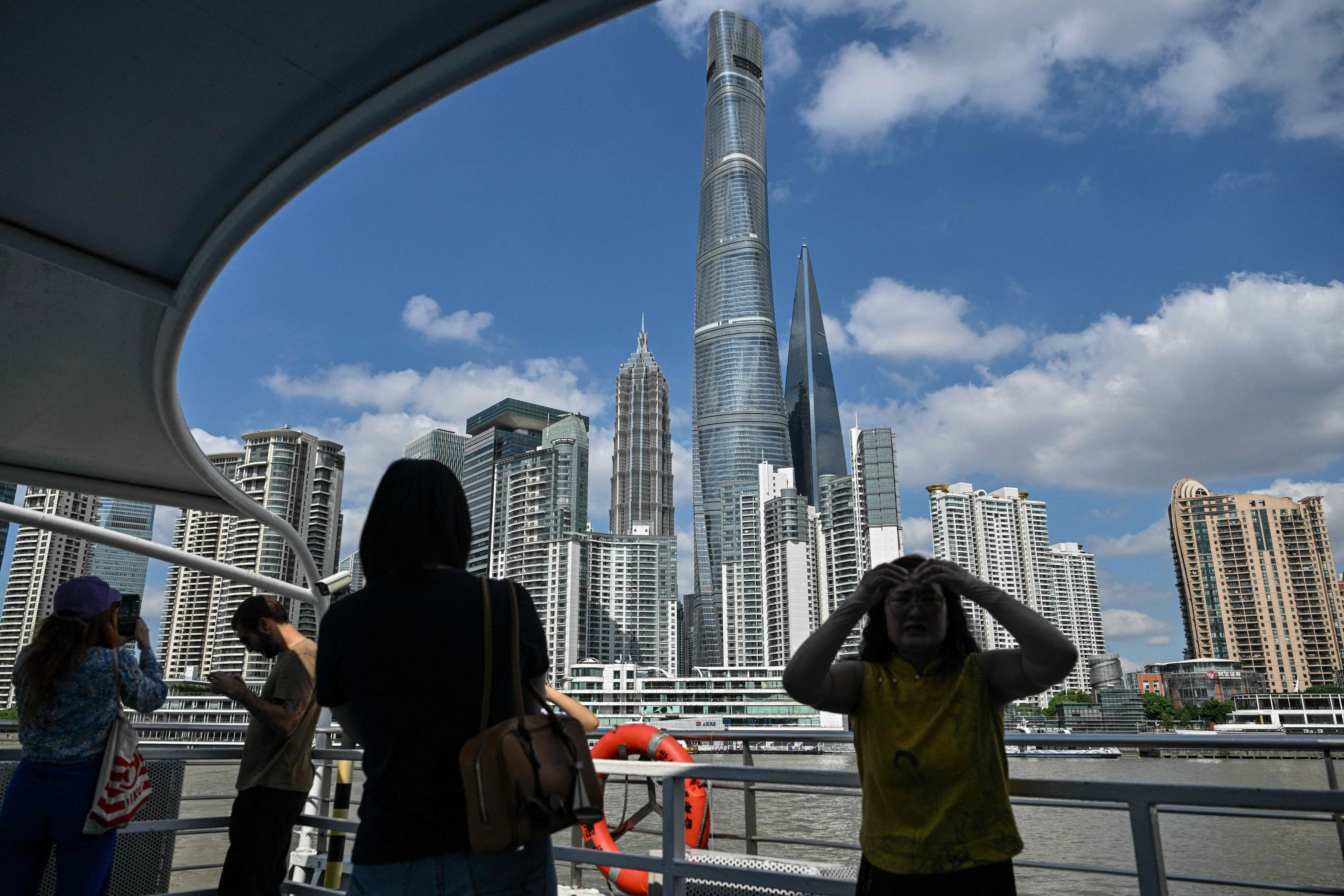 People sail on a ferry on the Huangpu River past the financial district of Lujiazui in Shanghai on 23 September 2024. (Hector Retamal/AFP)