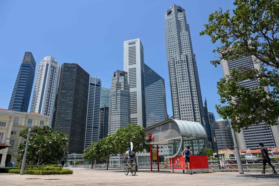 People pass by along the river quay at the financial business district in Singapore on 20 April 2021. (Roslan Rahman/AFP)