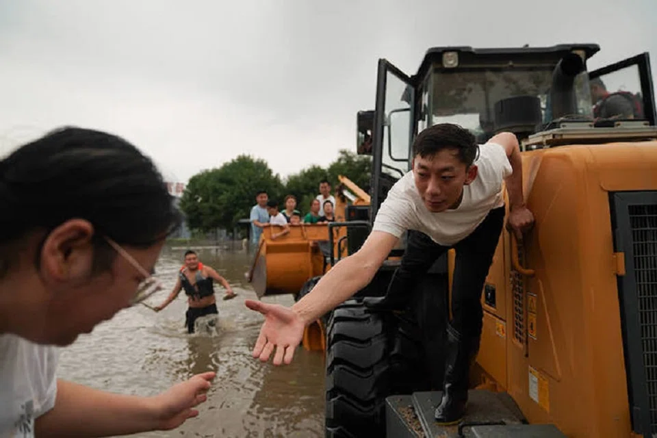 A rescuer is helping a resident to get on a vehicle in Zhuozhou on 1 August 2023.