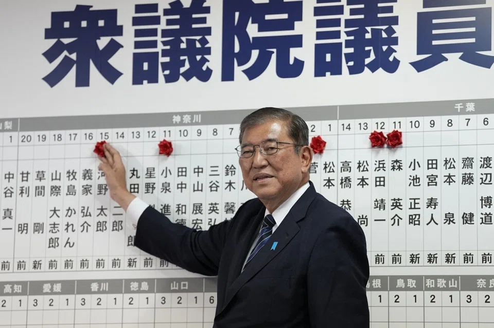 Shigeru Ishiba, Japan’s prime minister and president of the Liberal Democratic Party (LDP), places a paper rose on an LDP candidate’s name, to indicate a victory in the lower house election, at the party’s headquarters in Tokyo, Japan, on 27 October 2024. (Toru Hanai/Bloomberg)