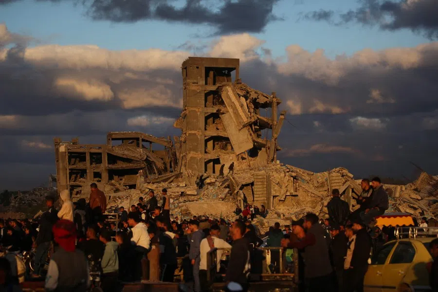 Displaced Palestinians stand next to destroyed houses in Nuseirat camp in the central Gaza Strip on 19 December 2025. (Eyad Baba/AFP)