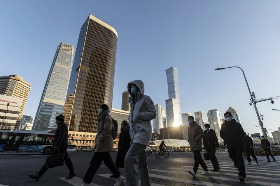 Pedestrians cross a road in front of buildings in the central business district in Beijing, China, on 23 November 2021. (Qilai Shen/Bloomberg)