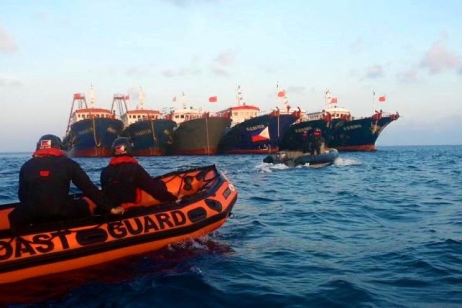 Philippine Coast Guard personnel are seen onboard rubber boats as they sail near Chinese vessels believed to be manned by Chinese maritime militia personnel at Whitsun Reef, South China Sea, in a handout photo distributed by the Philippine Coast guard 15 April 2021. (Philippine Coast Guard/Handout via Reuters)
