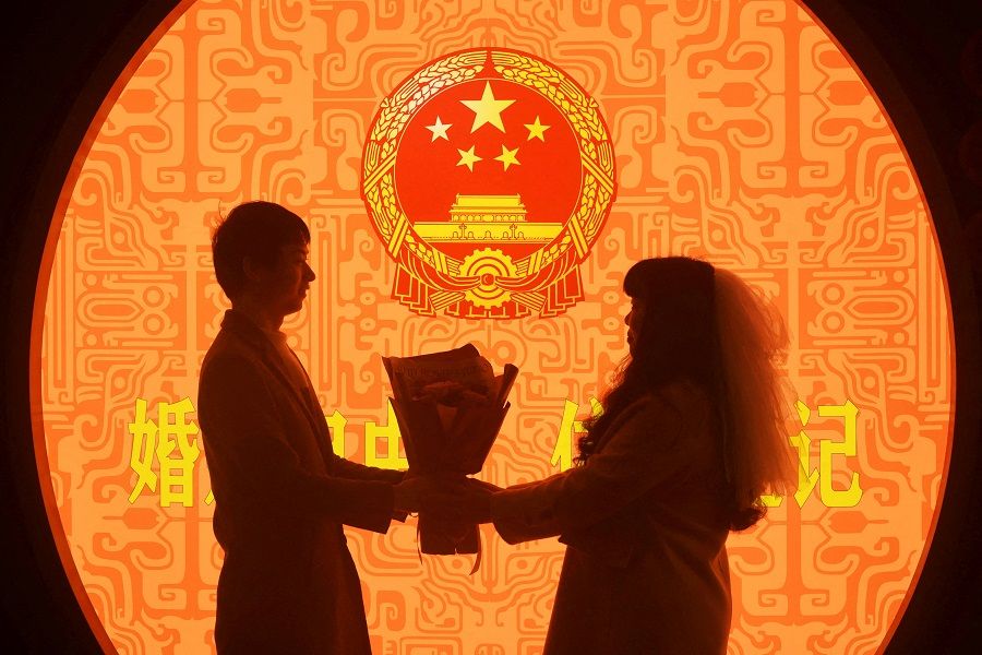 A newlywed couple poses for pictures on Valentine's Day at a marriage registration office in Hangzhou, Zhejiang province, China, 14 February 2023. (China Daily via Reuters)