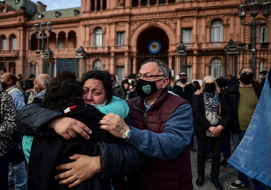 People embrace outside the Casa Rosada government house during the "march of the stones" in homage to Covid-19 victims, in Buenos Aires, Argentina, on 16 August 2021. (Ronaldo Schemidt/AFP)