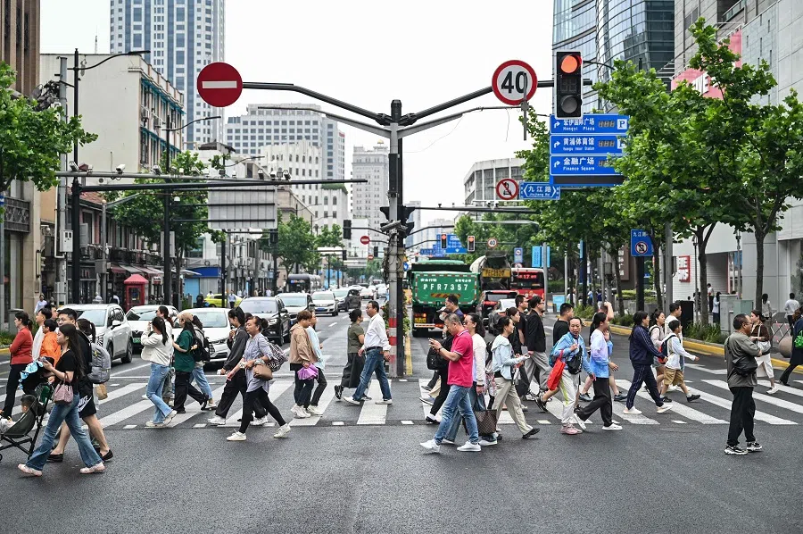 People cross a street in the Huangpu district in Shanghai, China, on 6 June 2024. (Hector Retamal/AFP)