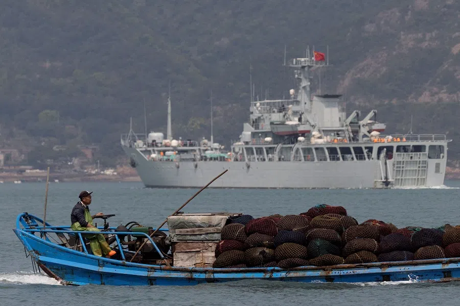 A fishing boat sails past a Chinese warship during a military drill off the Chinese coast near Fuzhou, Fujian Province, across from the Taiwan-controlled Matsu islands, China, on 11 April 2023. (Thomas Peter/Reuters)