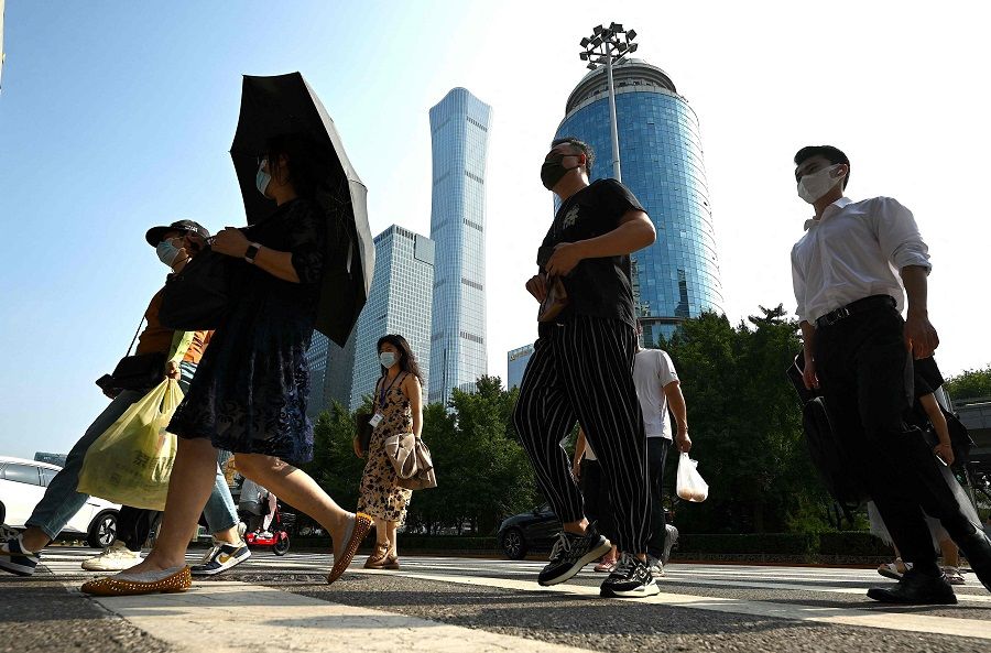 People walk along a street in Beijing, China, on 26 July 2022. (Noel Celis/AFP)