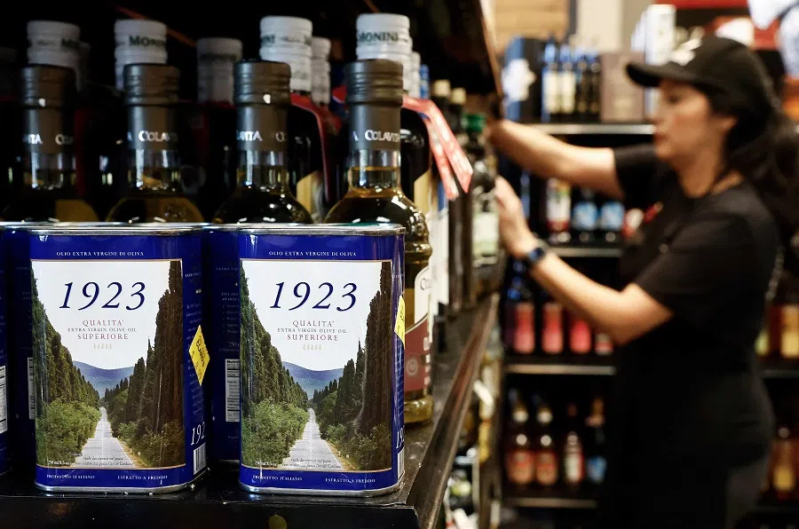 A worker restocks imported Italian olive oil at Claro’s Italian Market on 4 April 2025 in Arcadia, California. (Mario Tama/Getty Images via AFP)