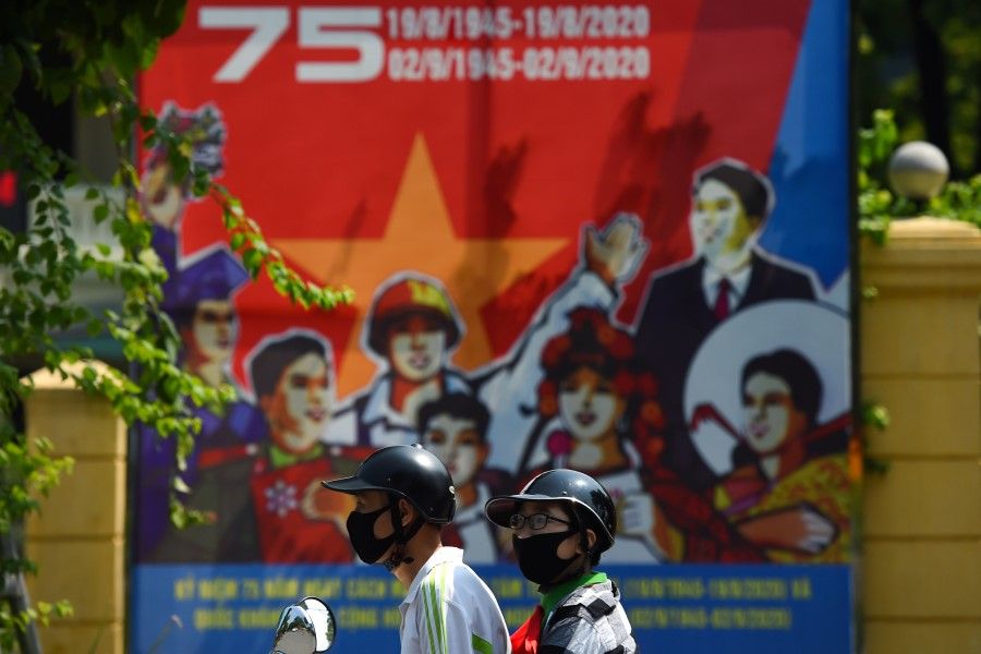 People on motorbike drive past a banner marking the 75th anniversary of Vietnam's National Day on 1 September 2020. (Nhac Nguyen/AFP)