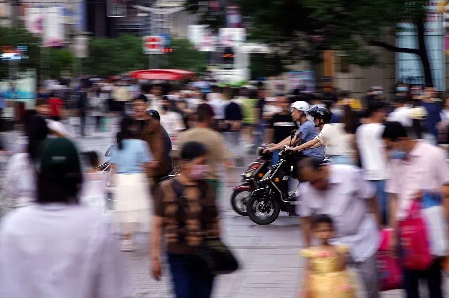 People ride scooters at Nanjing Road, a main shopping area in Shanghai, China, 10 May 2021. (Aly Song/Reuters)